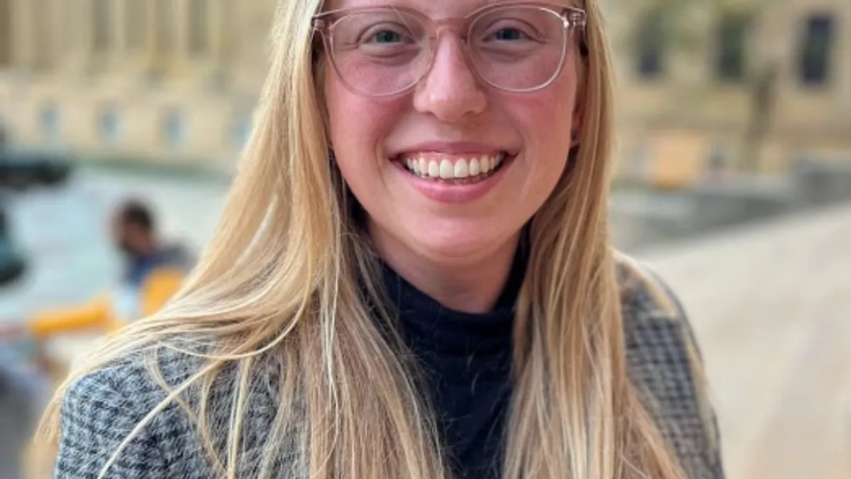 A woman with blonde hair and glasses smiles. Head shot of Beth Putney.
