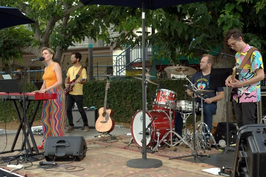 Four members of the SMCC Virginia Road Band play outdoors. From left to right people are playing: keyboard, electric guitar, drums, and bass guitar.