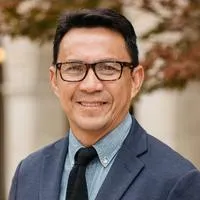 Bong Bringas, Commissioned Pastor. A smiling middle-aged man with glasses and a charcoal-blue suit.